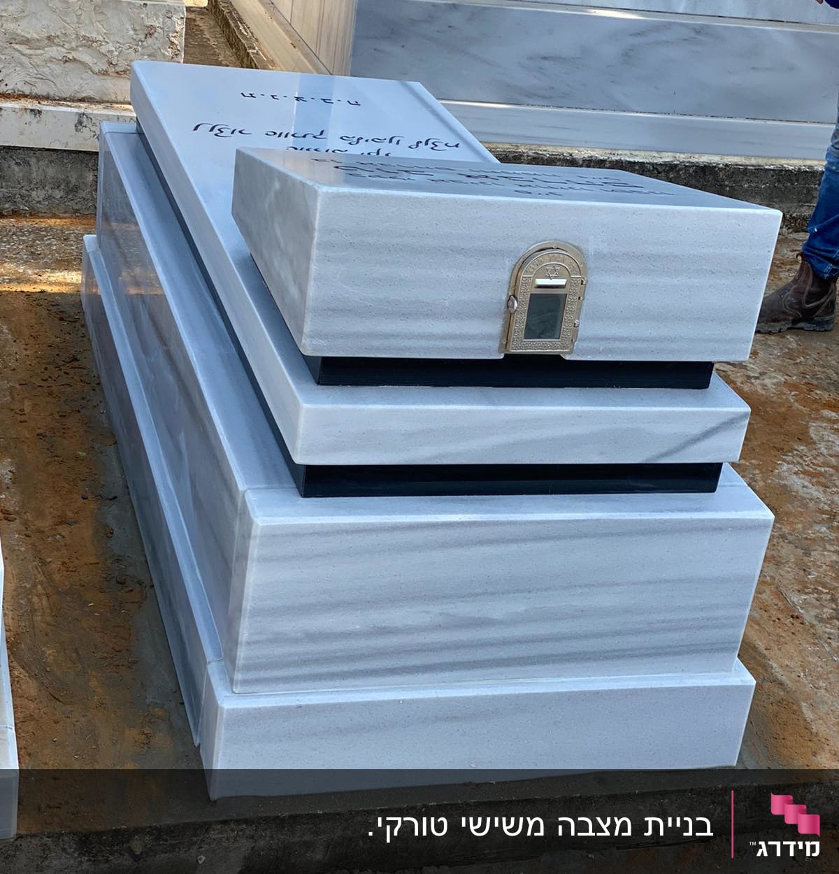 מצבה מאבן עם כיתוב ודלת מתכת קטנה